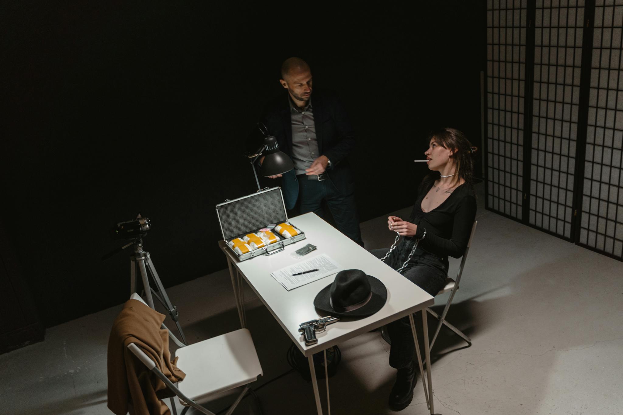 A tense indoor interrogation scene depicting a suspect and law enforcement setup.