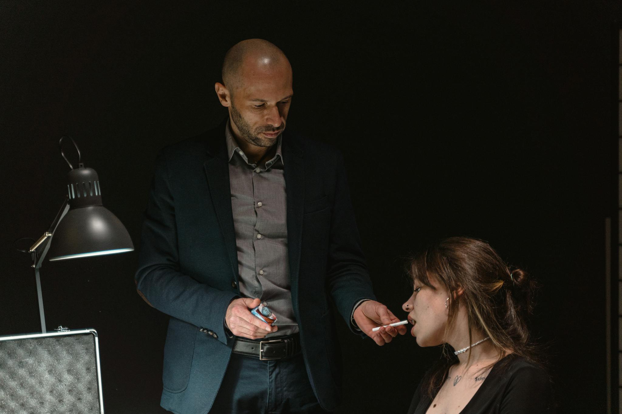 Intense interrogation scene featuring a man and woman under a dim light.